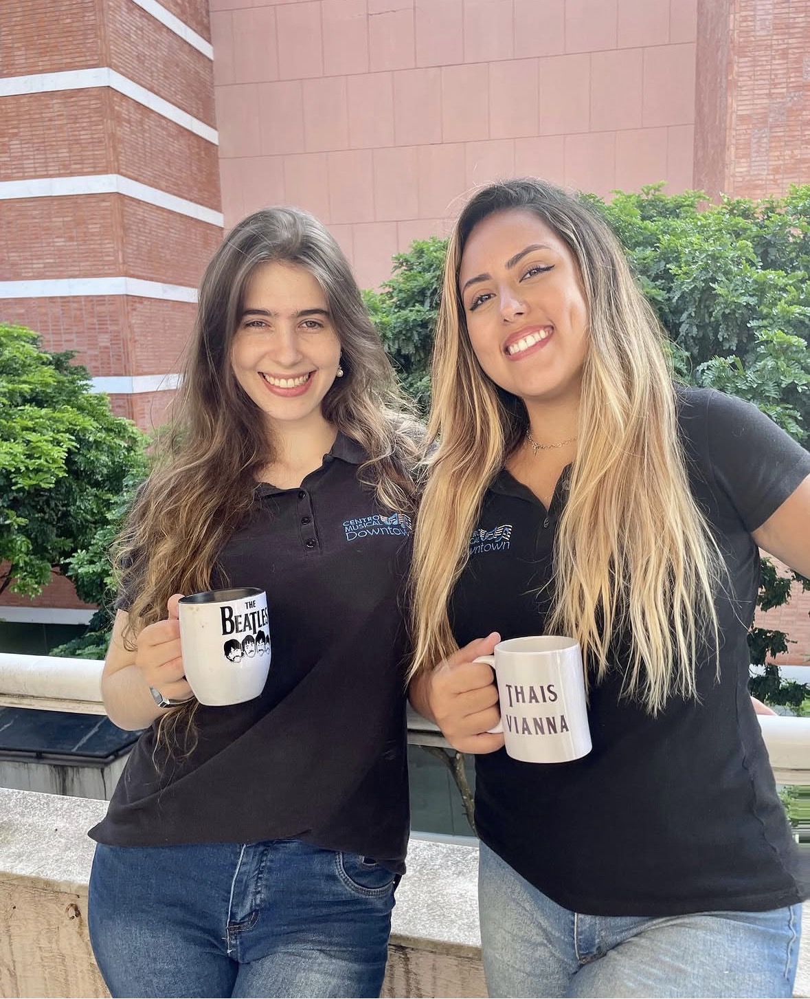 Duas professoras com canecas na varanda com vista para as árvores