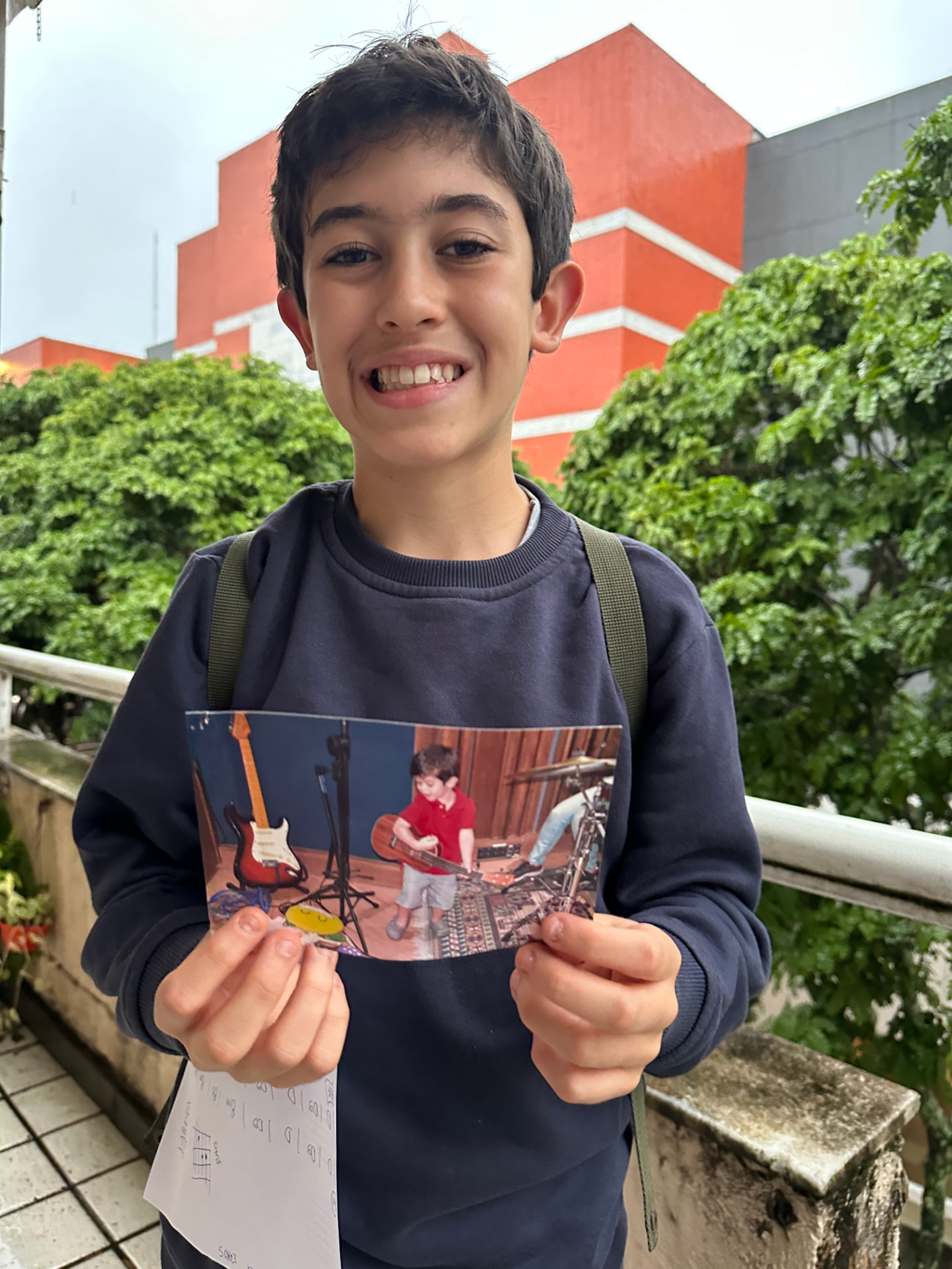 Aluno segurando uma foto antiga de infância tocando guitarra