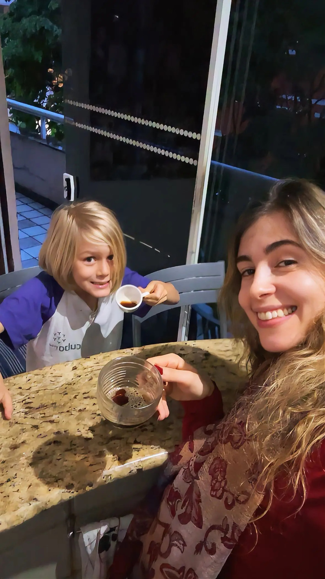 Aluna e criança com xícaras na bancada junto à janela