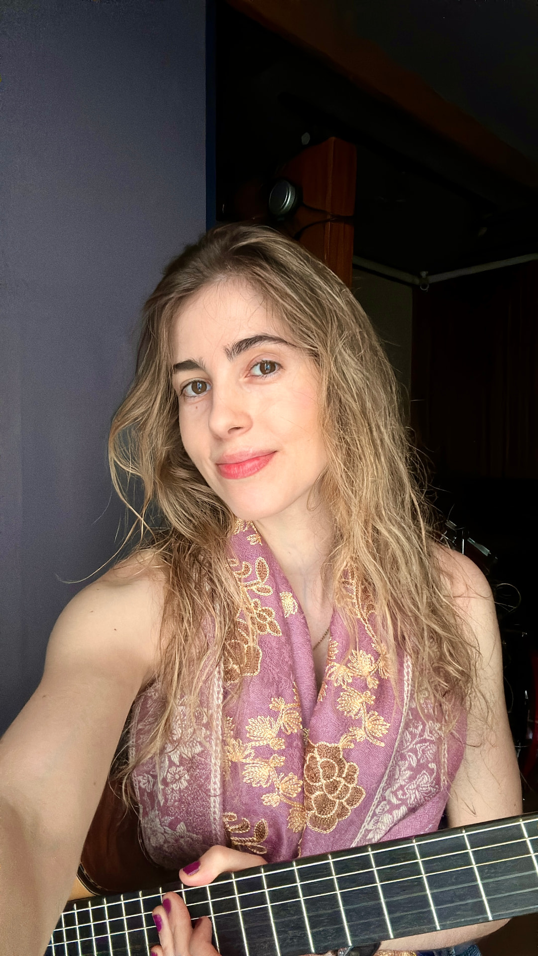 Selfie de aluna segurando o braço do violão