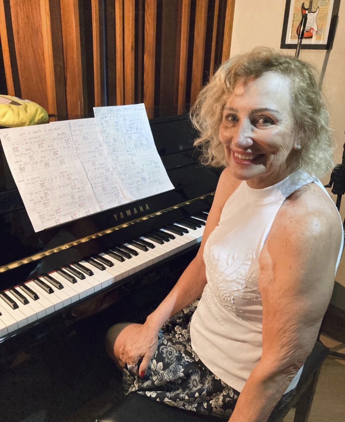 Aluna ao piano Yamaha com partituras e cifras manuscritas